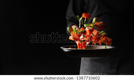 Sea cuisine, Professional cook prepares pieces of red fish, salmon, trout with vegetables.Cooking seafood, healthy vegetarian food and food on a dark background. Horizontal view. Banner