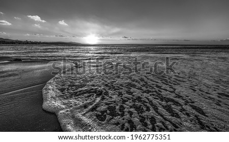 Sea foam in Alghero shore at sunset. Sardinia, Italy. Black and white effect