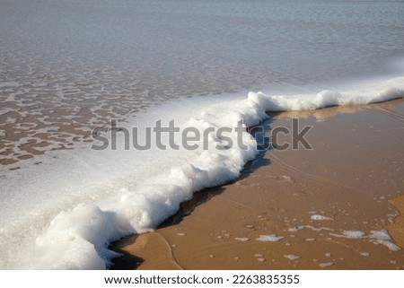 sea foam on sand beach coast ocean wave coming on sandy view low tide