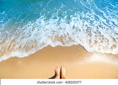Sea foam, waves and naked feet on a sand beach. Holidays, relax, summer background
