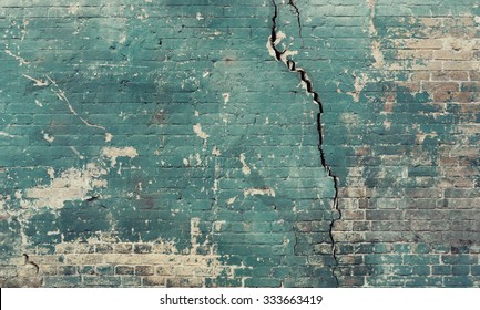 Sea green broken cracked brick wall.