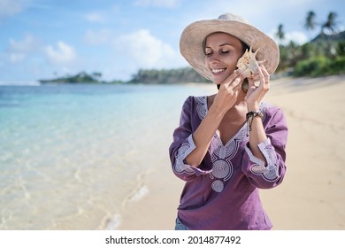 Sea In Her Hands. Close Up Of Young Woman Listening To Big Shell On The Beach.