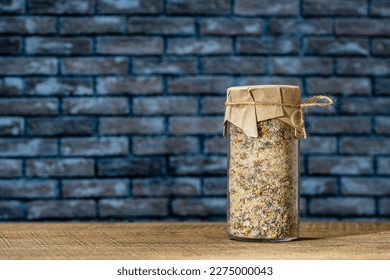 Sea himalayan salt with dry lavender and chamomile flowers in a glass jar on wooden table with the brick wall background, close up, copy space