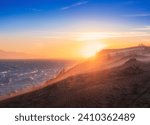 Sea or lake against backdrop of mountains with large sand dunes during sunset. Landscape with wind on the Kapchagay reservoir in Kazakhstan Almaty