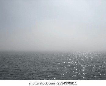 The sea lies still under a blanket of mist, creating an ethereal atmosphere. Fishing boats gently bob on the calm water, embodying tranquility. The soft fog envelops the horizon, enhancing the serene  - Powered by Shutterstock