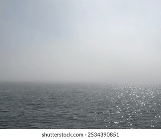 The sea lies still under a blanket of mist, creating an ethereal atmosphere. Fishing boats gently bob on the calm water, embodying tranquility. The soft fog envelops the horizon, enhancing the serene  - Powered by Shutterstock