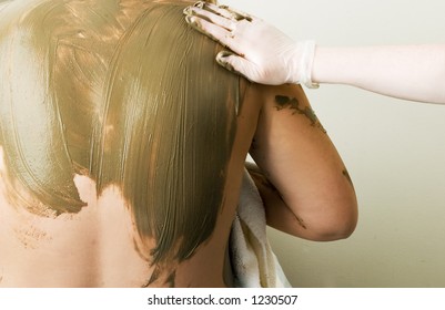 A Sea Mud Full Body Wrap At A Luxury Spa Being Applied To The Back And Shoulders.