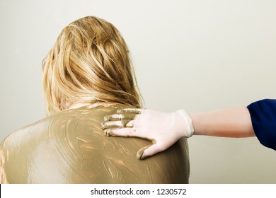 A Sea Mud Full Body Wrap At A Luxury Spa Being Applied To The Back And Shoulders.