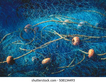 Sea nets - fishing equipment or tackle as texture backdrop with natural sunlight and shadow. Blue textured background of fishing nets close-up, marine design for craft of fishermen.