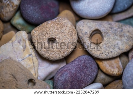 Sea pebbles of different colors with holes.