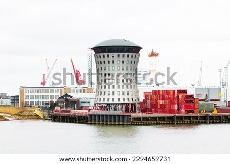Sea port in Rotterdam with a pilot observation tower and containers on the territory.