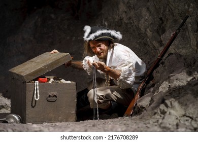 Sea robber captain of pirate ship armed with treasure chest in cave. Concept historical halloween. Filibuster cosplay. - Powered by Shutterstock