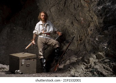 Sea robber captain of pirate ship armed with treasure chest in cave. Concept historical halloween. Filibuster cosplay. - Powered by Shutterstock