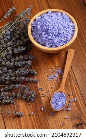 Sea Salt With Lavender In A Bamboo Bowl And In A Wooden Spoon And Dried Lavender Flowers Are Located On A Brown Wooden Table. Closeup. Top Down View.