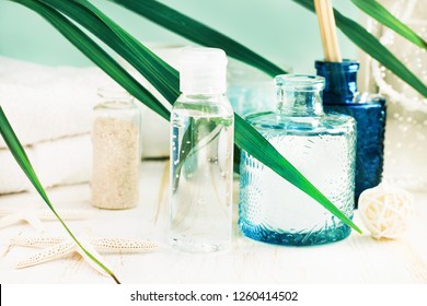 Sea salt mineral rich skin care spray, spa treatment facial toner. Blue glass jars, sea salt, palm leaves & towels, blue fresh toned.