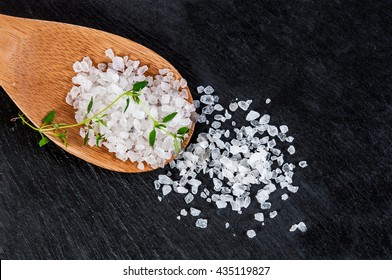 Sea salt on a wooden spoon over black slate background, selective focus, close up, salt,... 