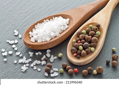 Sea salt and peppercorns on wooden spoons