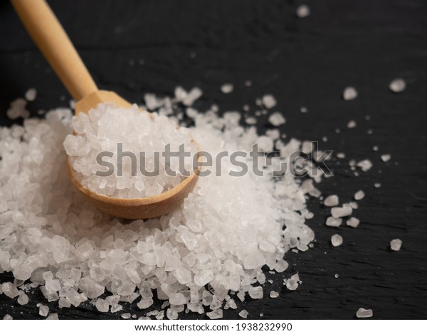 sea salt, a pile of sea salt in a\
wooden spoon on an old wooden background\
close-up
