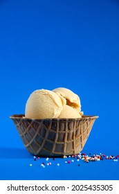 Sea Salted Caramel Gelato In A Waffle Bowl With Blue Background And Colored Candies Vertical