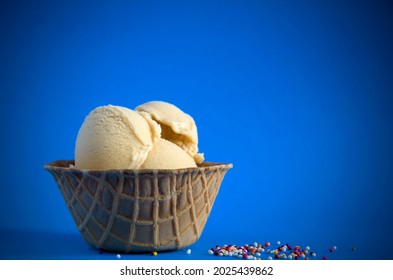 Sea Salted Caramel Gelato In A Waffle Bowl With Blue Background And Colored Candies Vertical