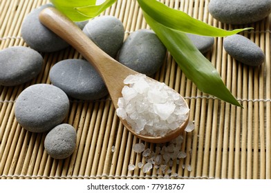 sea salts in wooden spoon with stones on bamboo stick straw mat - Powered by Shutterstock