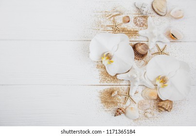 Sea Shells With Sand And Orchid Flowers On A White Wooden Background