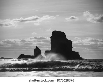 Sea stack sharp silhouette by sunset sky. Evening light on the rocks, boulders and cliff face of Talisker Bay, Isle of Skye