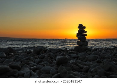 Sea stones standing on top of each other against the backdrop of a sunset on the seashore. - Powered by Shutterstock