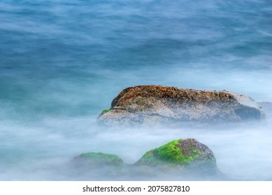 Sea stones in the water of the Mediterranean Sea. Water creates fog due to long exposure.