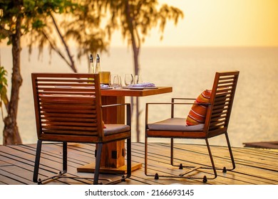 Sea Sunset In Modern Luxury Restaurant With Terrace. Outdoor Restaurant At The Beach With Pair Of Chair. Table Setting At Tropical Beach Restaurant. Elegant Hotel Or Resort Restaurant.