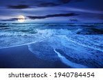 sea tide on a cloudy sunrise. green waves crashing golden sandy beach in full moon light. storm weather approaching. summer holiday concept