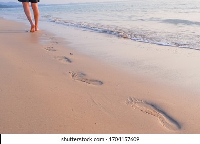 Sea vacation. someone walking on the beach. Beach travel, man walking on sand beach leaving footprints in the sand. Closeup detail of male feet and golden sand. Selective focus.trail barefoot feet