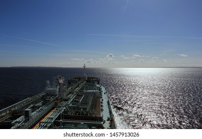 Sea vessel tanker on the background of a calm sea with beautiful clouds, blue sky and aircrafts trails.