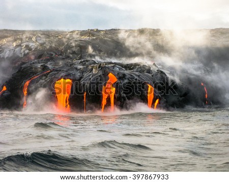 Sea view of Kilauea Volcano in Big Island, Hawaii, United States. A restless volcano that has been in business since 1983. Shot taken at sunset when the lava glows in the dark as jumps into the sea.