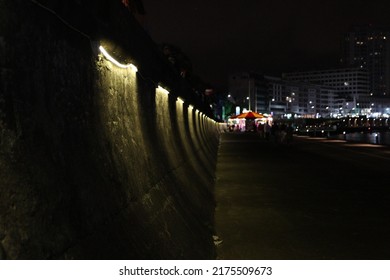 Sea Wall Merry Go Around On The Back Ground. Images At Night Of Flags And People Having Fun