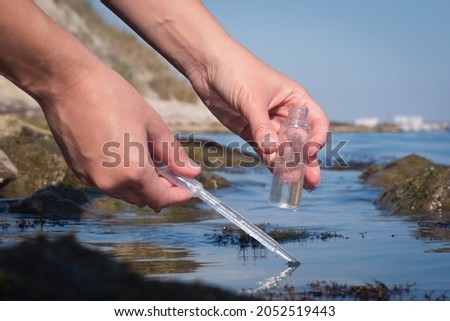 Sea water pollution concept. The scientist is taking  water sample of sea water close up concept.