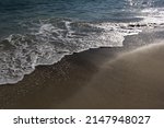 Sea water waves on sandy summer beach into sun light 