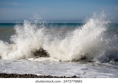 A sea wave breaks against the rocks, water splashes in the sky. Tidal wave. - Powered by Shutterstock