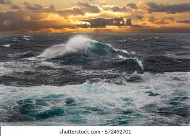 sea wave during storm in atlantic ocean with sunset on background