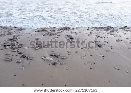 The sea wave run on sandy beach with small stones, top view. Soft tidal for publication, design, poster, calendar, post, screensaver, wallpaper, card, banner, cover, website. High quality photography