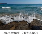 Sea waves crashing on the rocky shore at the resort of Agia Marina on the Greek island of Crete in Europe.