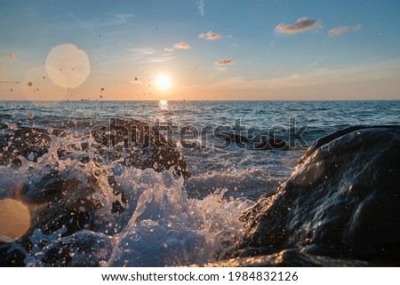 Sea waves crushing over the big rocks with beautiful sunset sky background