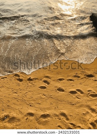 sea waves on beach sand. Foot trails on sand