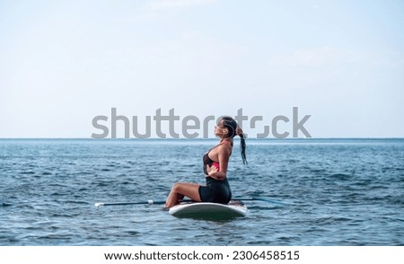 Sea woman sup. Silhouette of happy young woman in pink bikini, surfing on SUP board, confident paddling through water surface. Idyllic sunset. Active lifestyle at sea or river