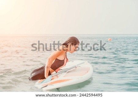 Sea woman sup. Silhouette of happy young woman in pink bikini, surfing on SUP board, confident paddling through water surface. Idyllic sunset. Active lifestyle at sea or river.