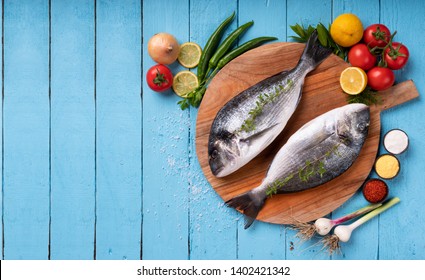 Seabream with vegetables on blue wooden background

