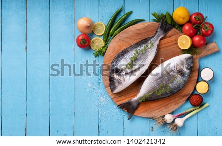 Seabream with vegetables on blue wooden background
