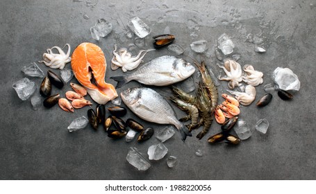 Seafood in assortment laid on ice, raw prawns, octopus, salmon steak and mussels on stone surface, top down view - Shutterstock ID 1988220056