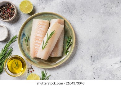 seafood background with ingredients for cooking. Raw cod loin fillet steak with aromatic herbs, spices, lime and olive oil on kitchen table. space for text - Shutterstock ID 2104373048