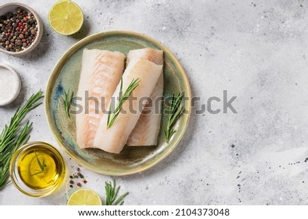 seafood background with ingredients for cooking. Raw cod loin fillet steak with aromatic herbs, spices, lime and olive oil on kitchen table. space for text